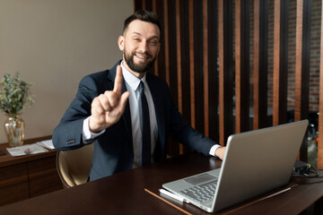 Bank employee in a suit working at a laptop in the office looking at the camera with a smile