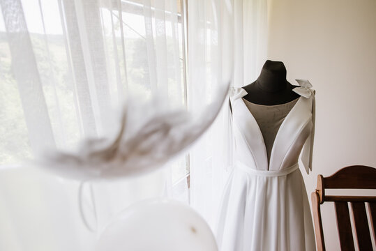 Stylish wedding dress on a mannequin in the morning by the window on the wedding day. Preparing for the wedding day