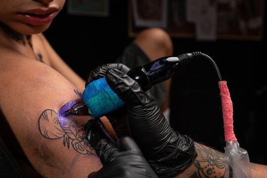 Unrecognizable tattooist making tattoo on arm of client