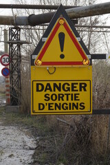 Yellow, red and black French traffic warning sign 'Danger! Exit of heavy vehicles' in industrial area, flashing warning lights (vertical), Seltz, Grand Est, France