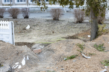 The trenches were dug near school in village under ruined fence and trees after battle. War of...