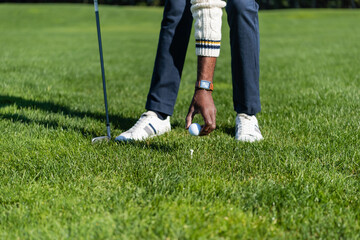 Fototapeta premium cropped view of african american man placing ball on golf tee.