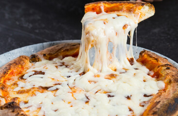 Tasty take slice of pizza with cheese. Appetizing separate piece of round pizza stretching melted...