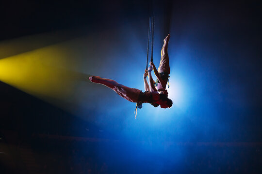 Circus actress acrobat performance. Two boys perform acrobatic elements in the air.