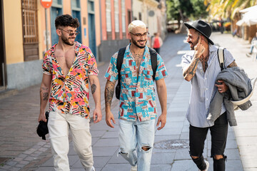 Three happy young men walking in the city, talking to each other, having fun. Multiethnic group of...