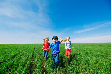 Naklejka na ściany i meble Running kids in green field during summer.