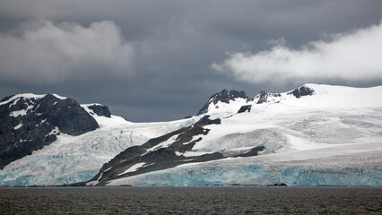 Glacier meeting the Southern Ocean at the base of rugged mountains in Antarctica