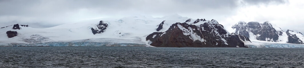 Fototapeta na wymiar Panorama of a glacier meeting the Southern Ocean at the base of rugged mountains in Antarctica