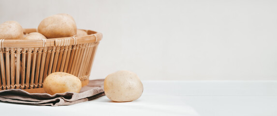 farmer grown potatoes in a basket on a white table. banner, copy space. local food, vegetarian meal