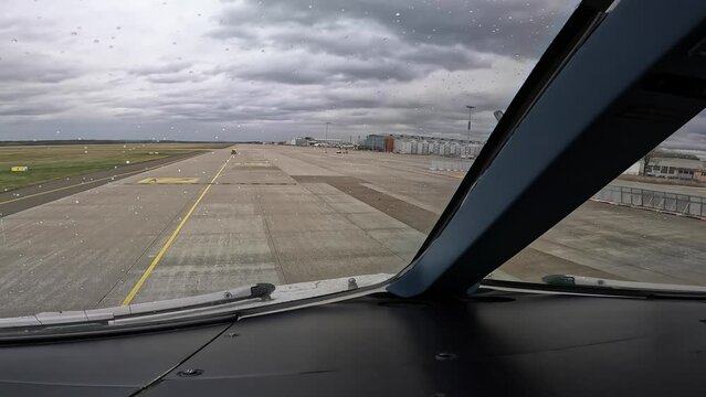 Cockpit view of a taxi in maneuver on a modern wide-body passenger, cargo aircraft , at  Airport, The Captain follows the yellow black Follow Me car  on a cloudy and rainy day