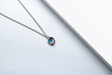Fototapeta premium Silver chain necklace with blue diamond pendant on white background