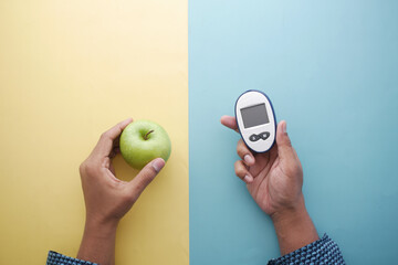  holding diabetic measurement tools, apple on table 