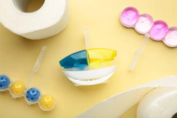 Toilet balls and toilet paper on yellow background. Clean the toilet bowl with cleaning and refreshing balls.