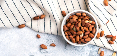 Ground nuts food photo flatlay. Peanut heap in a small ceramic bowl. High key food photography with nuts. Snack healthy vegan organic ingredient