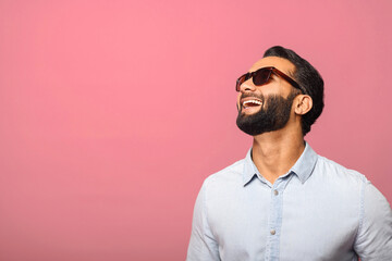 Cheerful Indian man in sunglasses laughing toothy, carefree hispanic guy in blue shirt standing and...