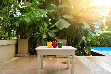 Close up of The red, yellow and green bell peppers placed on a white wooden table Inside the garden beside the pool in a luxury condo in Thailand. Concept for health and vitamins.