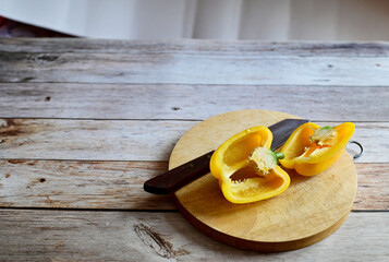 Fresh yellow bell peppers (capsicum) has been cut with a knife and a wood chopping block isolated on wooden background. Concept for health and vitamins.