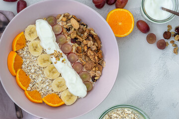 healthy muesli bowl for breakfast with oranges, bananas and grapes