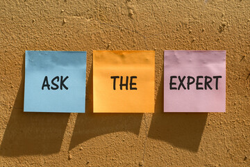 Ask the experts. Sticky note with ask the experts inscription pinned on a orange wall