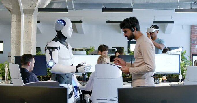 Indian man speaking to robot in office. Male developer checking work and moves of cyborg. Coworking space. Humanoid moving and executing instructions and orders. Artificial intelligence Startup.