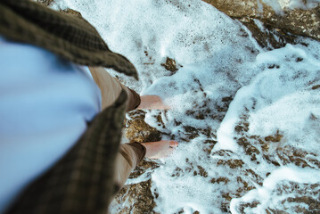 overhead view man barefoot walking by sea rocky beach