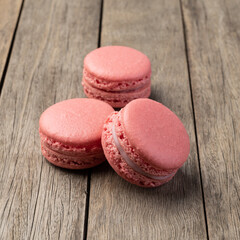 Three berry macarons stacked over wooden table