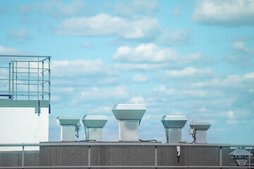 Industry background. Modern ventilation pipes on the roof against the blue sky.