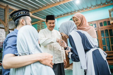 asian muslim family coming back home and shake their parent's hand during eid mubarak idul fitri...
