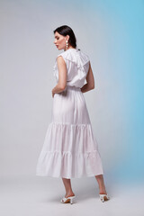 Beautiful woman fashion model makeup brunette hair perfect body shape tanned skin wear clothes summer collection organic long white silk dress stylish sandals shoes, accessory jewelry earrings date.