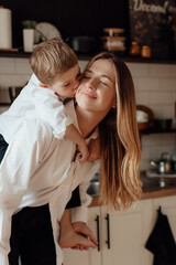 Happy little boy congratulating smiling mother and giving card with red heart during holiday...