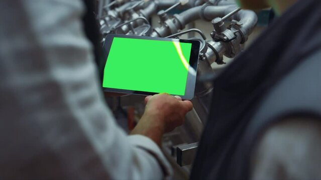 Engineer hands swiping tablet with chroma key screen at steal equipment closeup