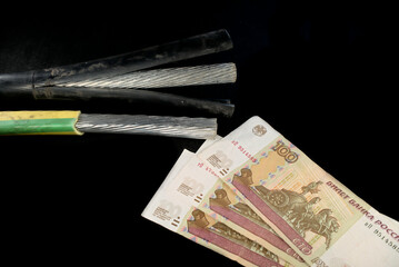Metal cables for the electric power industry and 100 Russian rubles on a black background