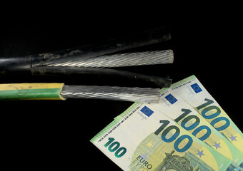 Metal cables for the electric power industry and 100 euros on a black background