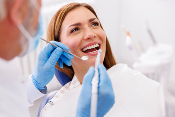 Dentist using dental drill while fixing patient's tooth