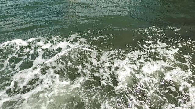 An amphibious vehicle moves down a boat ramp and enters the water. Window view.
