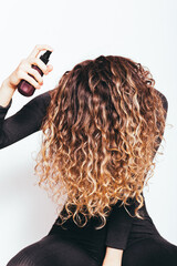 Young woman with long curly hair spraying