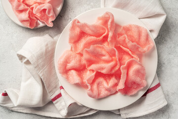 Shrimp chips in a white plate on a light cooking table. Krupuk udang in a plate on a culinary background
