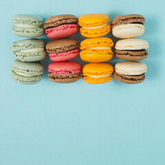 Pastel blue table top with colorful makarons pattern. The concept of minimal sweet food. Cookie concept
