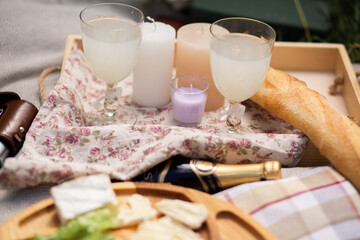 Romantic picnic on the grass. Glasses, champagne, baguette, blanket, books, candles.