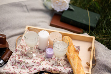 Wedding picnic on the grass. Glasses, baguette, blanket, books, candles.