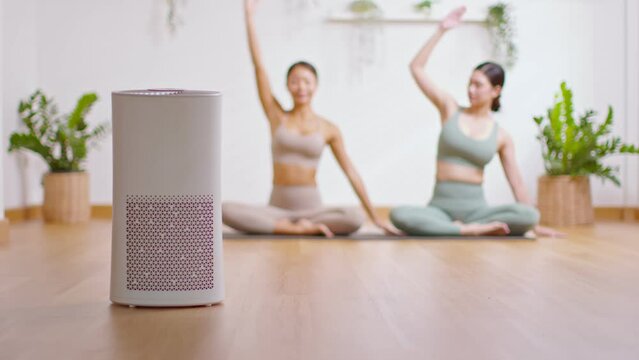 Air purifier in cozy white Living room for filter and cleaning removing dust PM2.5 HEPA at home with woman exercise yoga in background,for fresh air and fresh breath healthy life,Air Pollution Concept