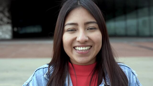 Young latin woman smiling on camera in the city