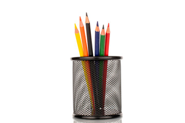 Several colored pencils in a metal glass, close-up, isolated on a white background.
