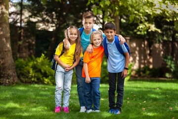 Fototapeta premium Group of happy school child with schoolbag in outdoor park