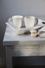 Two corrugated mugs on a white tray and a kitchen towel on a beige table against a white wall. Scandinavian style. Minimalism. Place for text