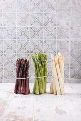 Green, white and purple asparagus on a kitchen background - 500451082