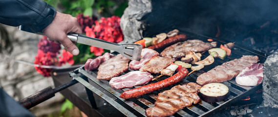 Man cooking meat on barbecue grill at bbq party