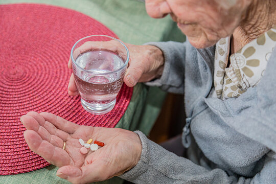 Alte Frau nimmt eine ganze Hand voll verschiedener Tabletten ein