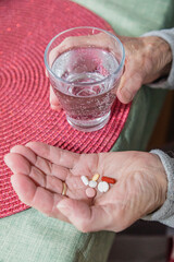 Alte Frau nimmt eine ganze Hand voll verschiedener Tabletten ein