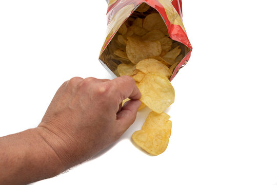 A Hand Taking Chip From A Bag Of Chips, Open And Front View. With Chips Inside And Outside The Bag. Isolated On White Background. Selective Focus. 